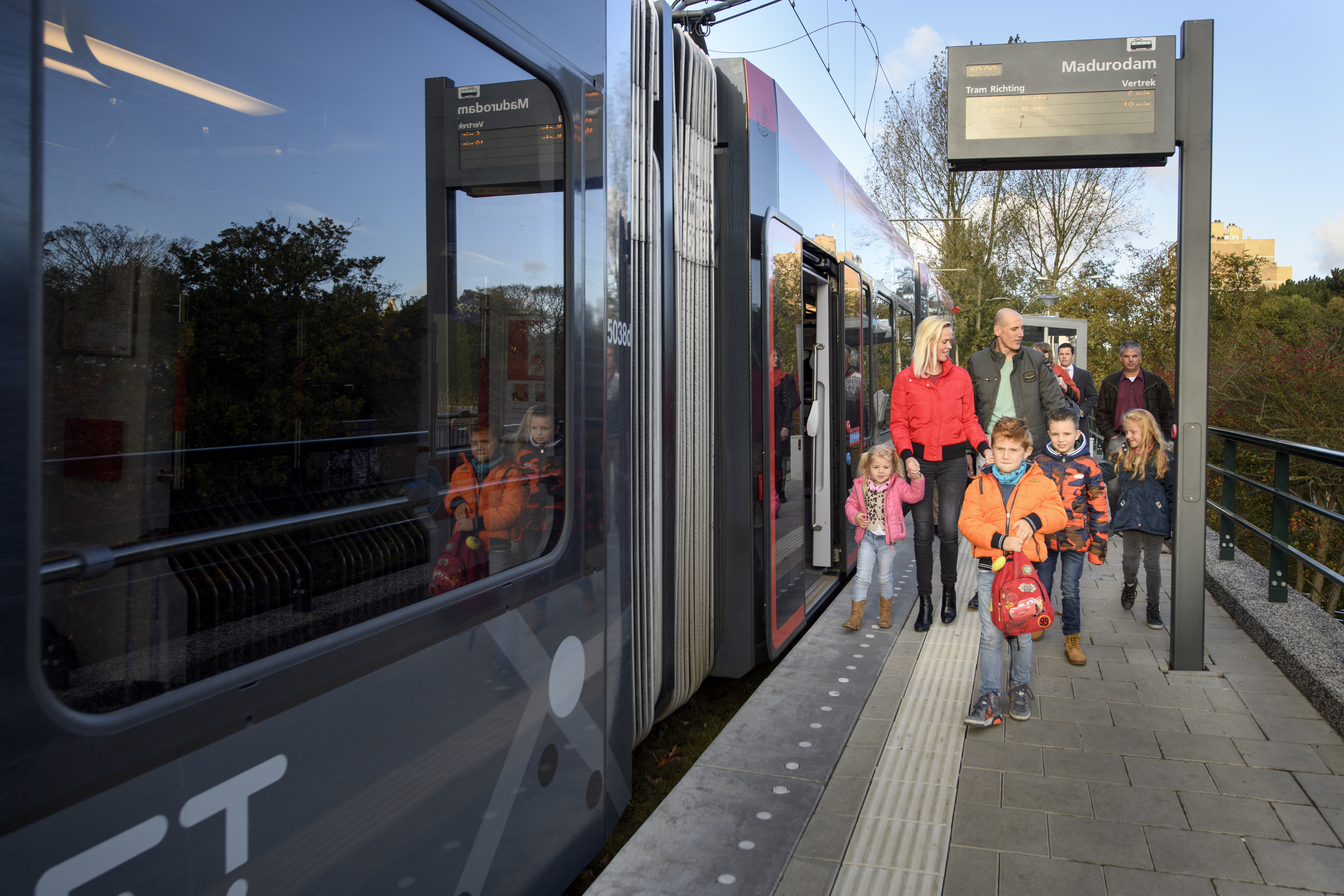 Reizigers met kinderen lopen naast HTM tram
