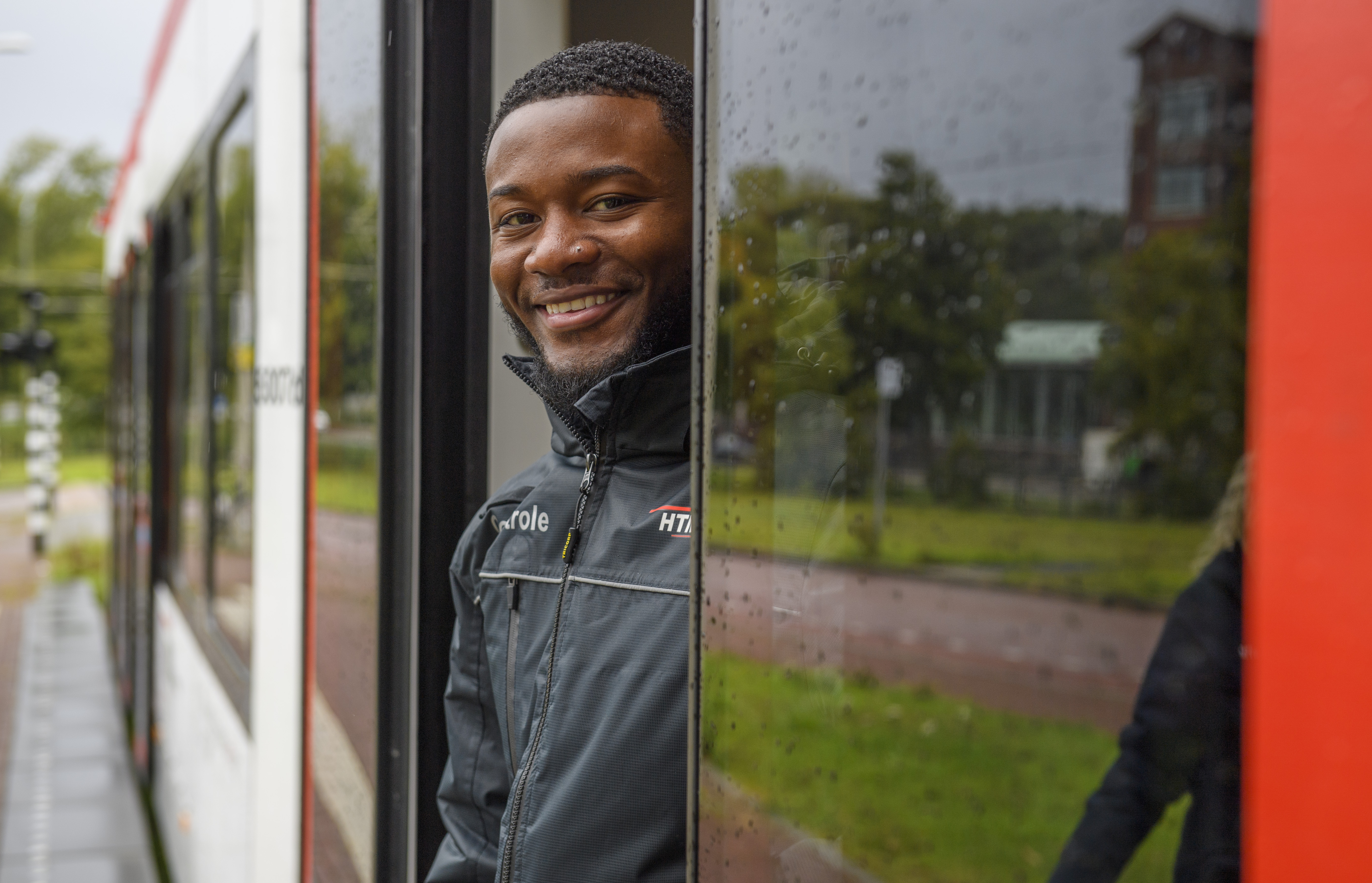 HTM boa staat in deuropening HTM tram en lacht naar de camera