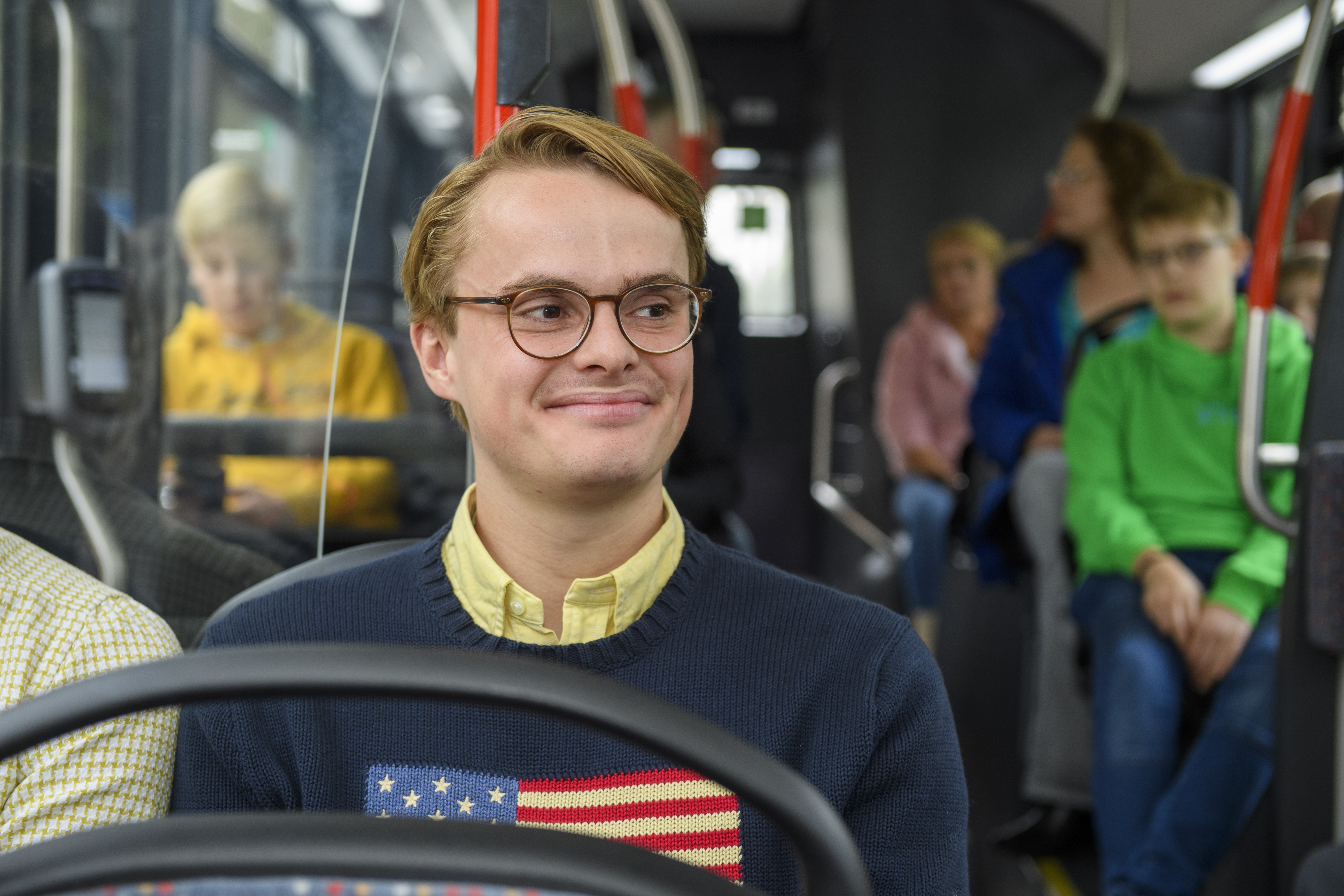 Jongen in zit HTM bus en kijkt lachend naar voren