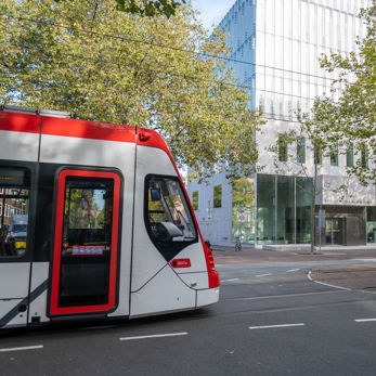 Zijaanzicht Aveniotram voor het gebouw van de Hoge Raad in Den Haag HTM Avenio rood-wit voor de Hoge Raad Den Haag