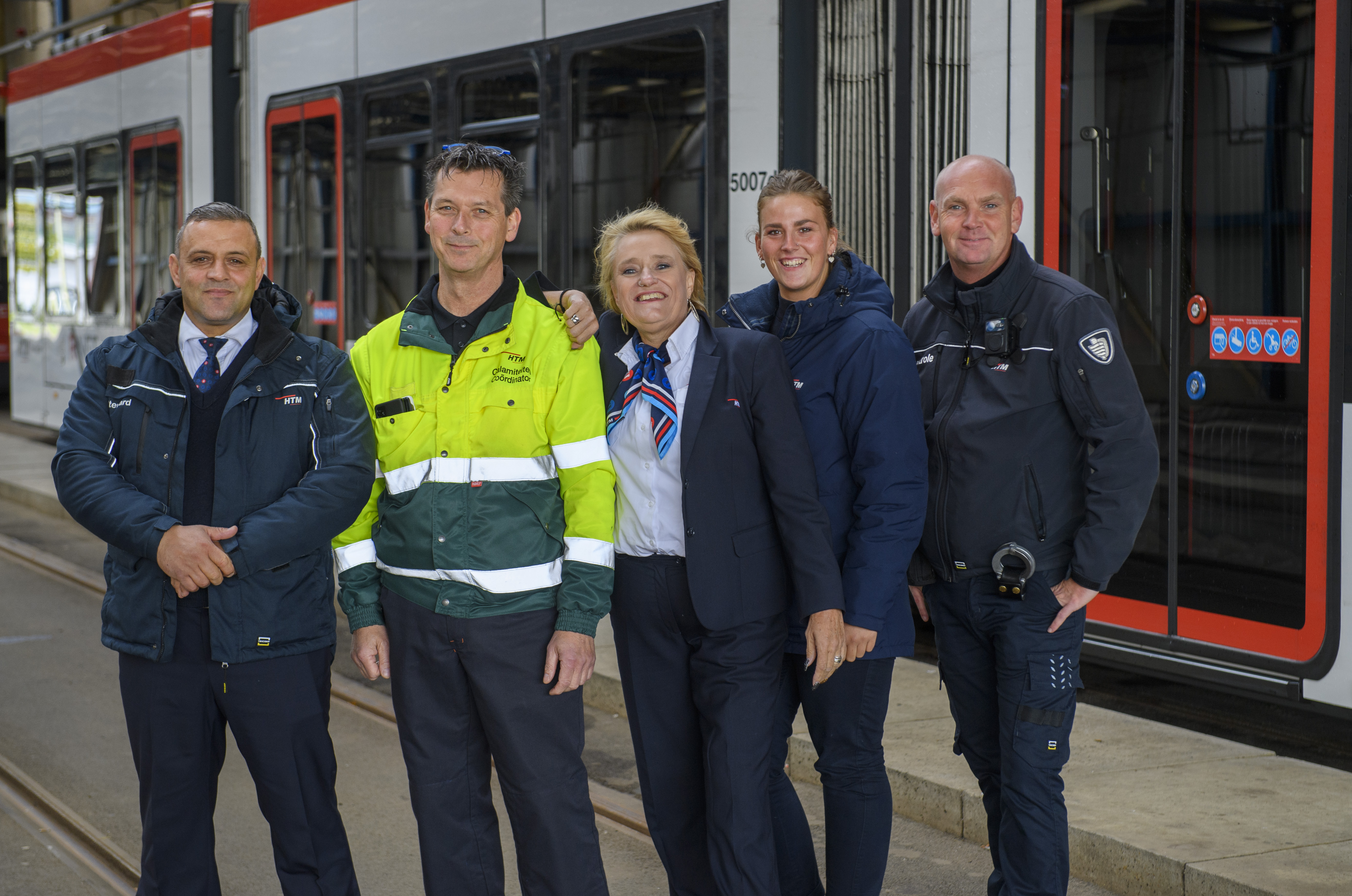 HTM medewerkers naast HTM tram kijken naar de camera