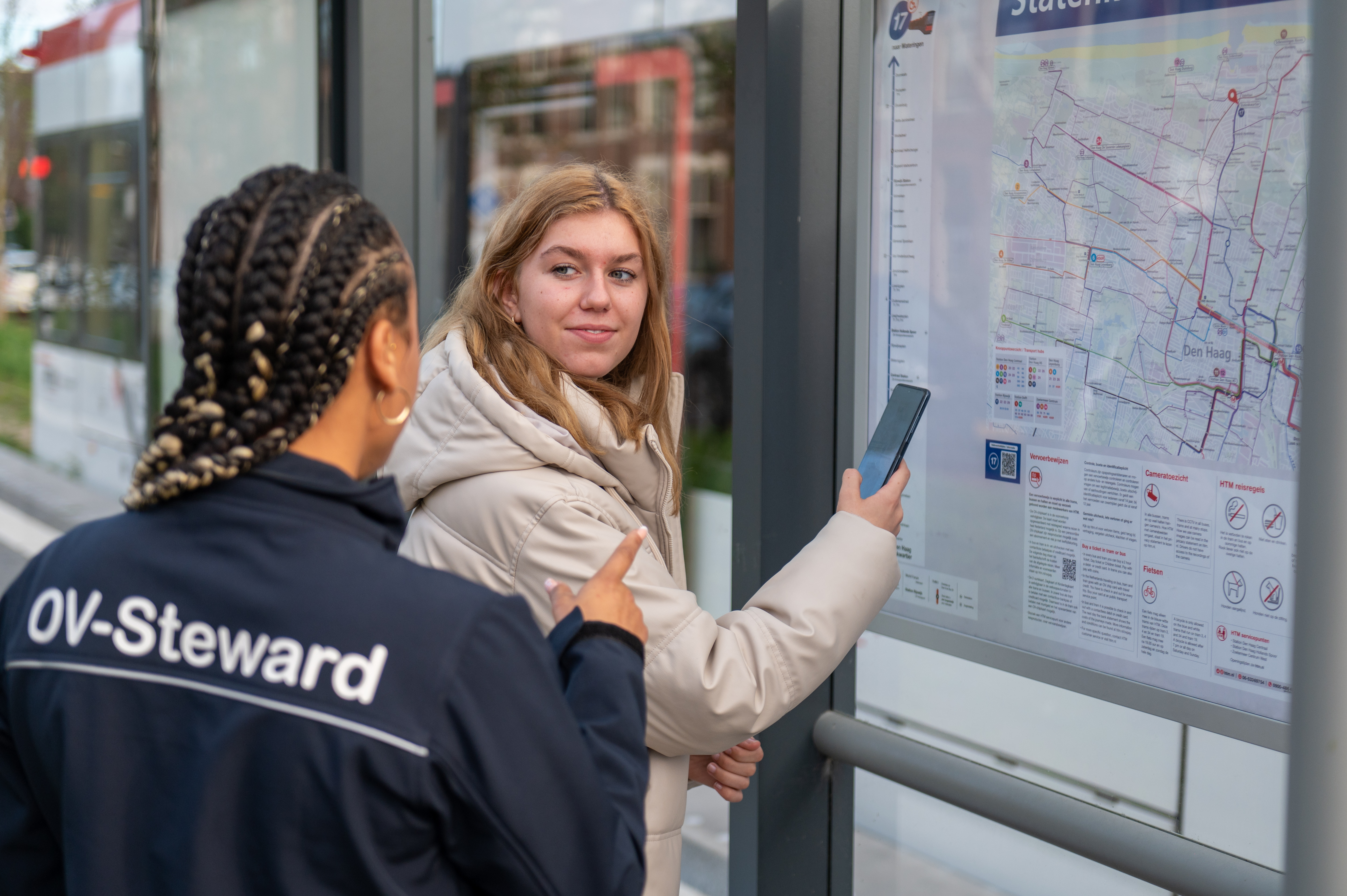 HTM steward met reiziger naast reisinformatie kaart